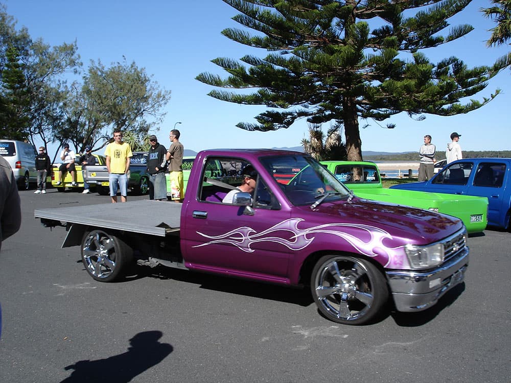 Purple metallic Toyota flatbed minitruck with white flame graphics and chrome wheels at coastal gathering at Half Way Havoc 2006 Nambucca Heads NSW - Minitruck Show Photos