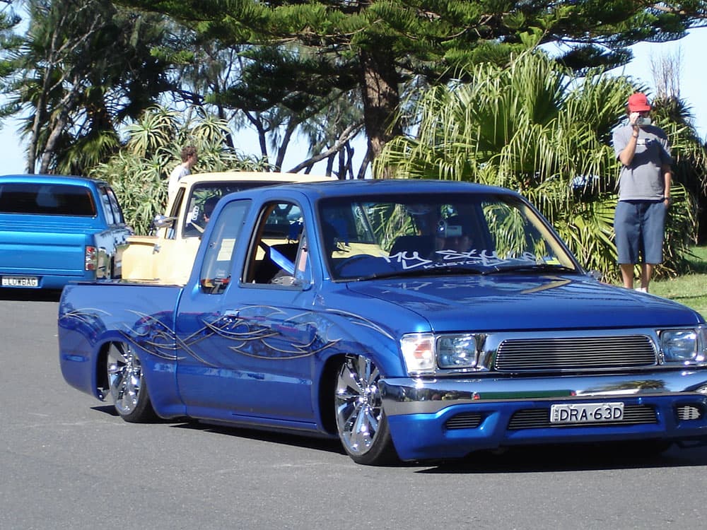 Metallic blue Toyota Hilux extended cab with tribal flame graphics and hood open at coastal event at Half Way Havoc 2006 Nambucca Heads NSW - Minitruck Show Photos