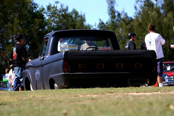 Matte black slammed Chevrolet C10 pickup with custom stance parked on grass at Half Way Havoc