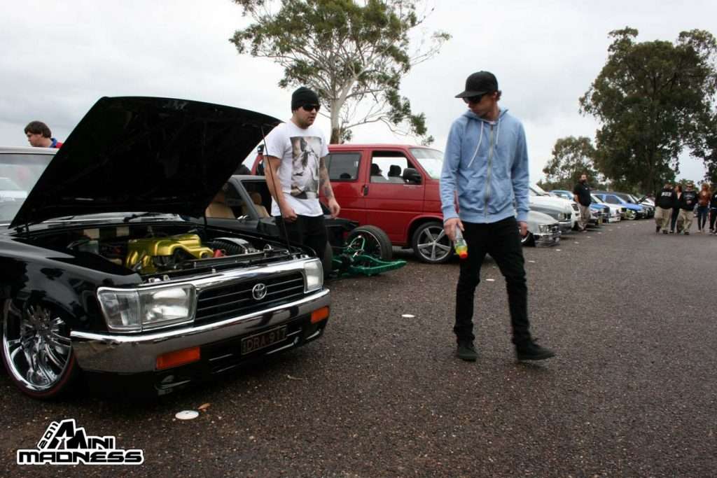 Black minitruck with yellow engine bay and chrome wheels with enthusiasts at Mini Madness 2011