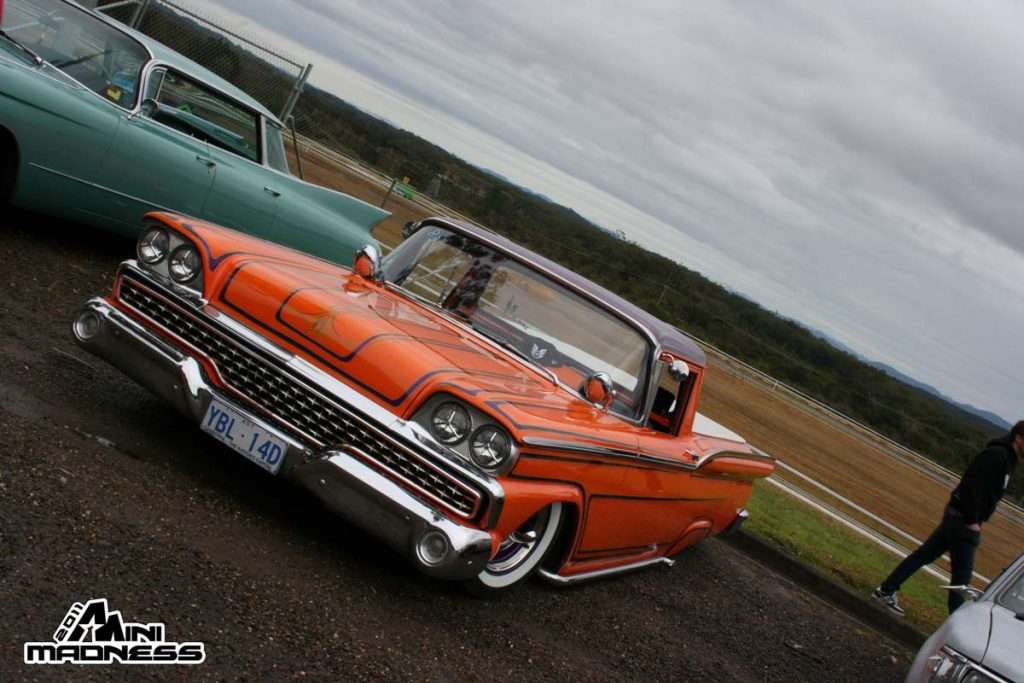 Orange vintage lowrider pickup with chrome grille and white wall tires at Mini Madness 2011 Port Macquarie