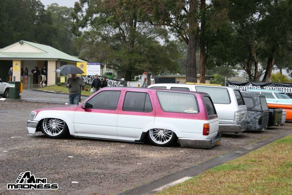 Pink and white two-tone custom SUV with chrome wire wheels in rain at Mini Madness 2011