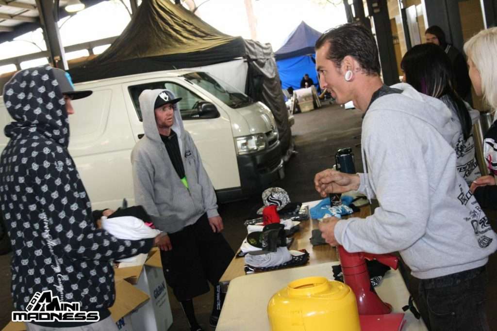 Attendees browsing merchandise vendor table at covered Mini Madness 2011 event