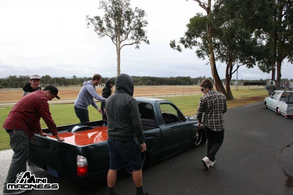 Group of enthusiasts gathered around custom minitruck with orange bed at Mini Madness 2011