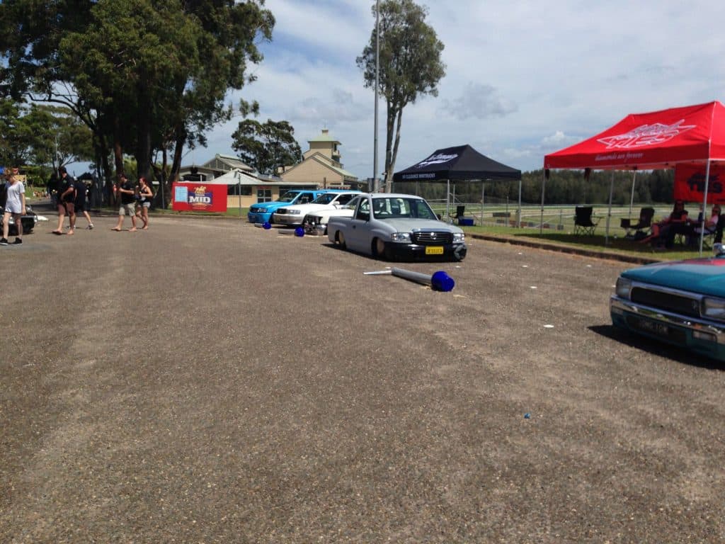 Event overview showing vendor tents and slammed trucks on gravel at Mini Madness 2014 Port Macquarie
