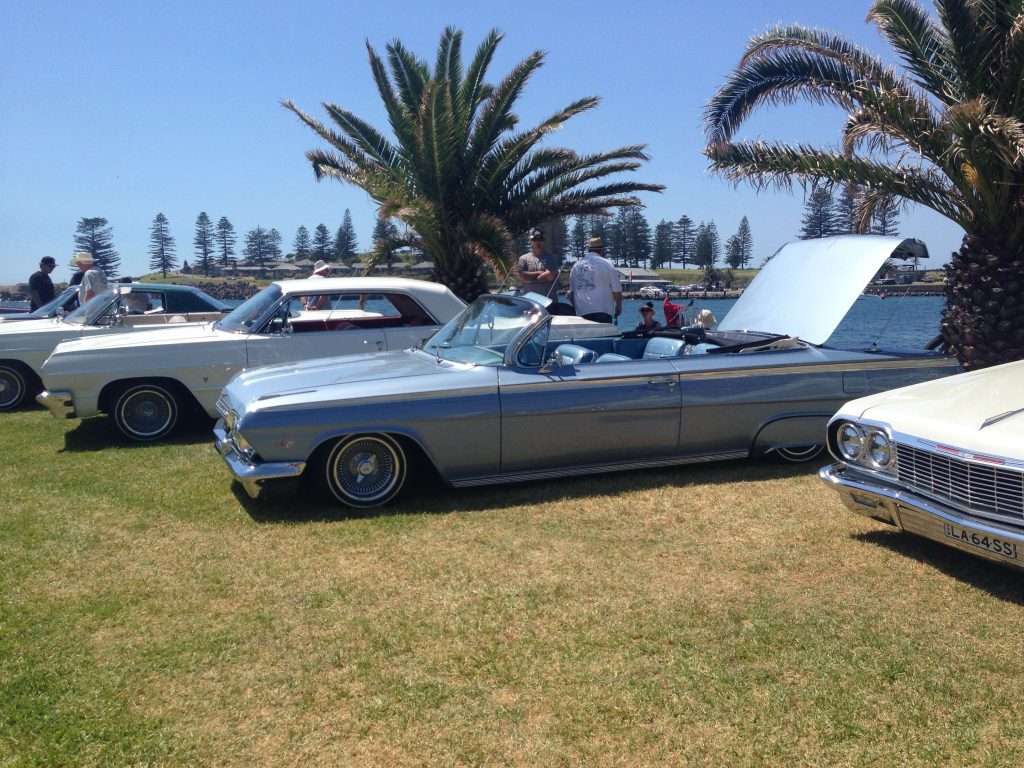 Classic lowriders lined up on waterfront grass at South Coast Showdown NSW
